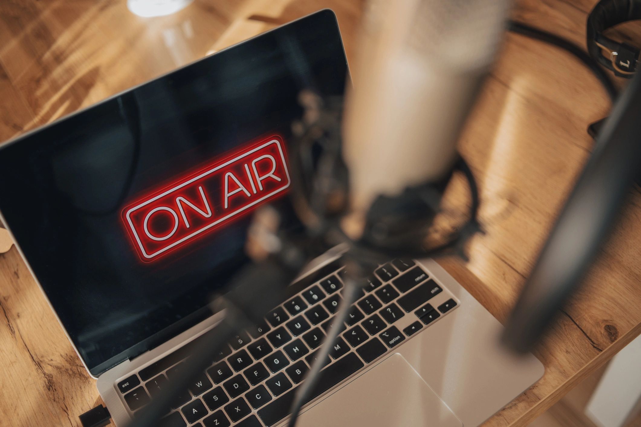 Overhead view of a laptop displaying an ON AIR sign with recording equipment